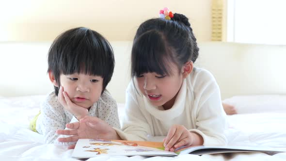 Cute Asian Children Reading A Book On White Bed alt