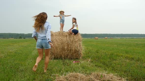 Mum Runs on the Field to her Kids Sitting on Haystack