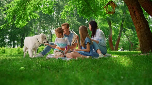 Happy Family Feed White Dog on Weekend Picnic alt
