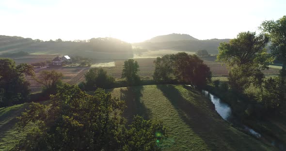 Aerial shoting backwards from a tree with the sun coming up on a beautiful summer morning. alt