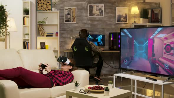 Woman Lying on Sofa Playing Video Games Using Vr Headset alt