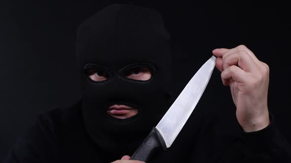 Terrorist in a balaclava with a flashlight in his hands, a criminal in a mask alt