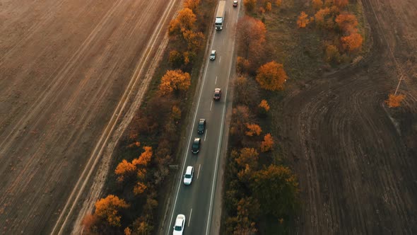 An Aerial View of Cars Driving Along a Highway During an Autumn Sunset alt