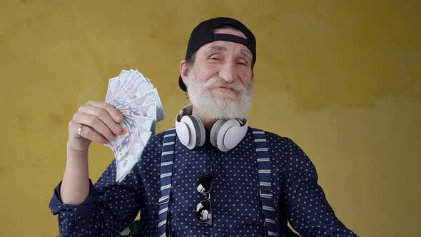  Modern Attractive Bearded 70-aged Man Posing on Camera with Many One Hundred Dollars Banknotes alt