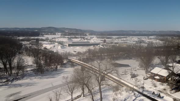 snow covered landscape with icy river and mountains in the background with blue sky.