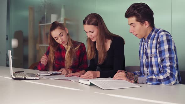 Concentrated Students Working on Their Homework Sitting Together at the Table and Drinking Coffee alt