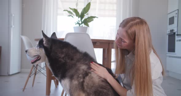 Portrait of Woman Sitting on the Floor and Hugging Her Pet Siberian Husky Dog