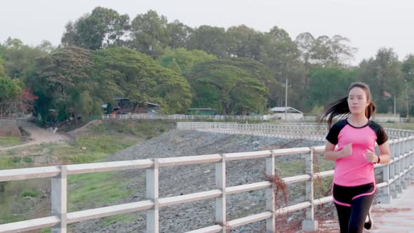 Young sport Asian woman running exercise for good health in pink sportswear on outdoor alt