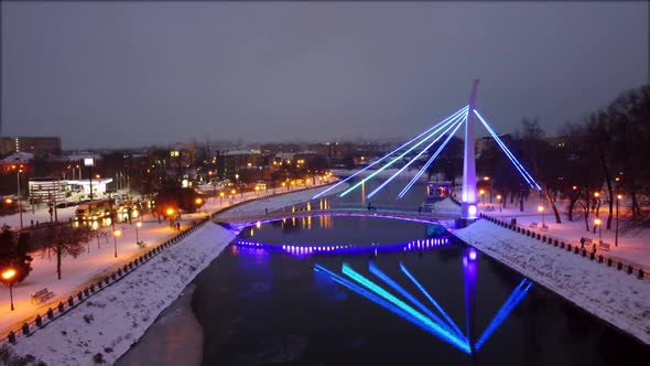 Illuminated bridge on winter river in Kharkiv city