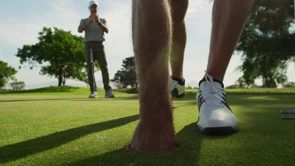 Caucasian male golfer reaching down a ball out of the hole on a golf course on a sunny day alt