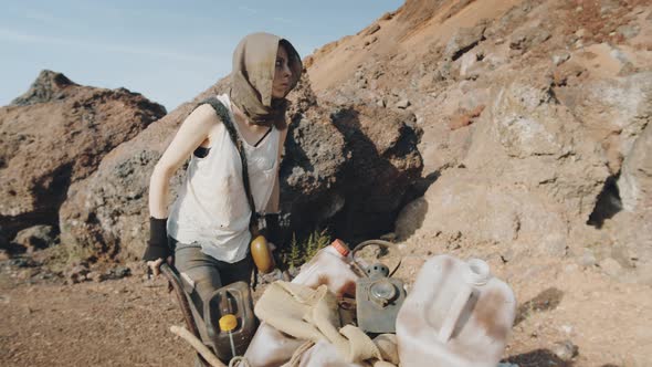 Post Apocalyptic Woman Pushing Cart in Rocky Desert alt