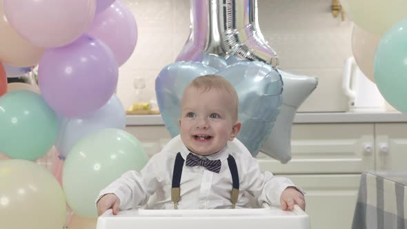 Happy Baby Boy at His First Birthday Party One Year Old Child Against the Background of Colorful alt