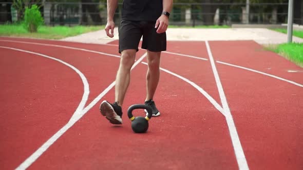 Close Up Footage of a Man in Black Sportswear Comes to Train with Weight Bob Outdoors on the alt