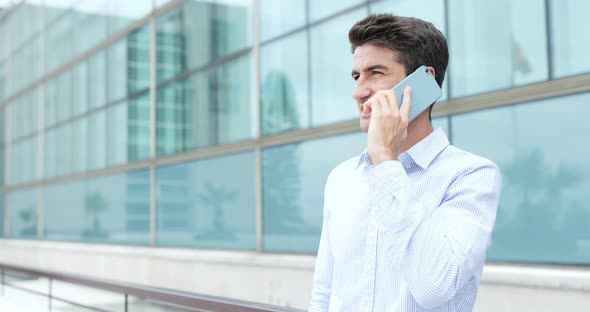 Hispanic man talk to cellphone outside office alt