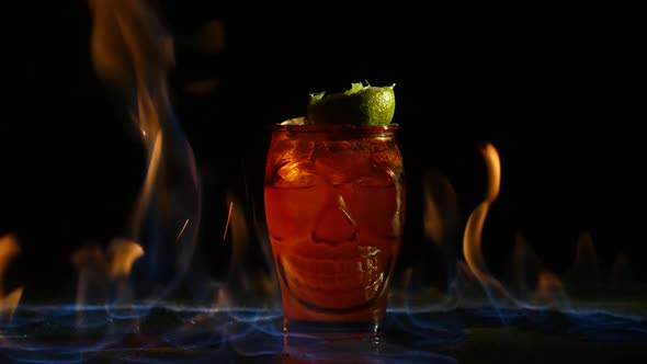 Original Red Glass with Cocktail and Lime on Top Are in Fire with Sparks in Black Background in