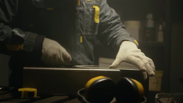 Metalworker in the workshop makes measurements with ruler alt