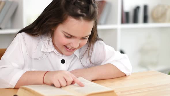 A little girl reads a book in the library alt