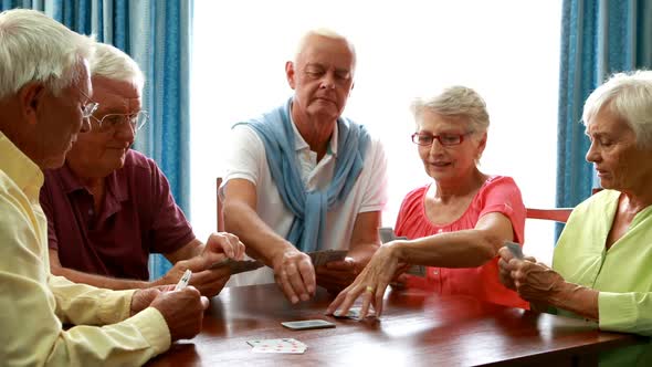 Senior friends playing cards in living room alt