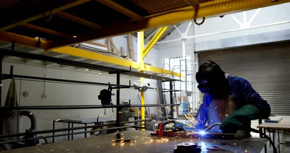 Female welder using blowing torch on a rod 4k alt