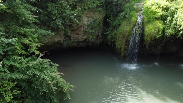 aerial view of a beautiful waterfall with blue lake in the forest.