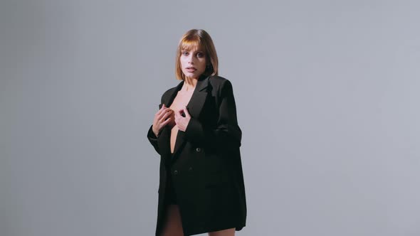 Provocative young caucasian businesswoman in a black suit jacket on a white background.	