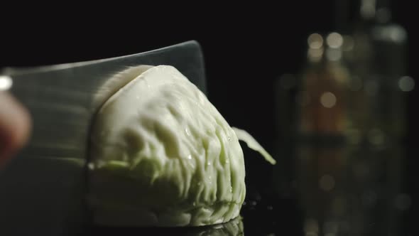 Cook Cutting A White Cabbage On A Black Table