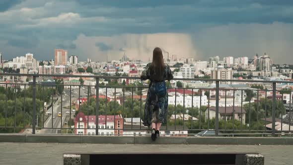 Stylish Woman Looks at Large Modern City From Viewing Deck alt