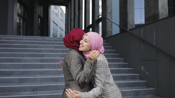 Two Young Muslim Women Wearing Hijab Headscarf Greet Each Other, Hug Eash Other, Modern Lifestyle