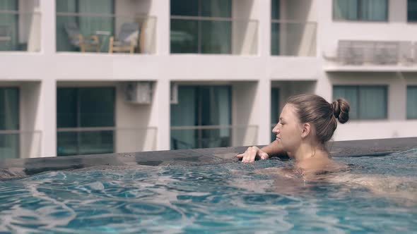 Pretty Lady in Black Bikini Swims and Leans on Pool Rim alt