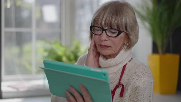 Shocked Caucasian Woman Shaking Head Reading Latest News on Tablet Standing Indoors alt