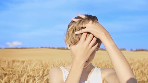 Portrait of a Boy with a Stylish Hairstyle Combing His Head and Looking at the Camera at the Wheat alt