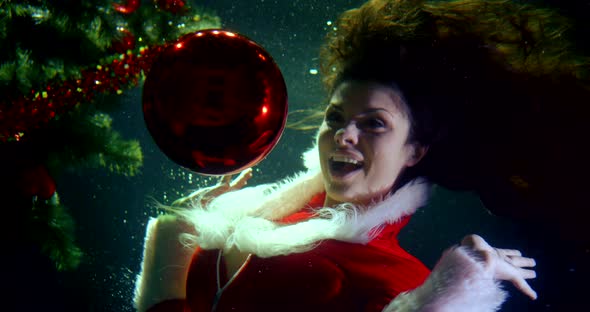 Portrait of a Bright Girl in a Christmas Red Suit, She Is Under Water, Next To Her Elegant Christmas alt