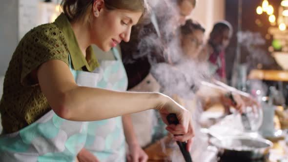 Woman Cooking Pasta in Pot during Culinary Master Class alt