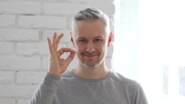 Okay Gesture by Middle Aged Man Sitting in Office alt