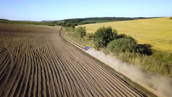 Top Down Aerial View of Fast Driving Car on Dirt Road Leaving Cloud of Dust Behind alt