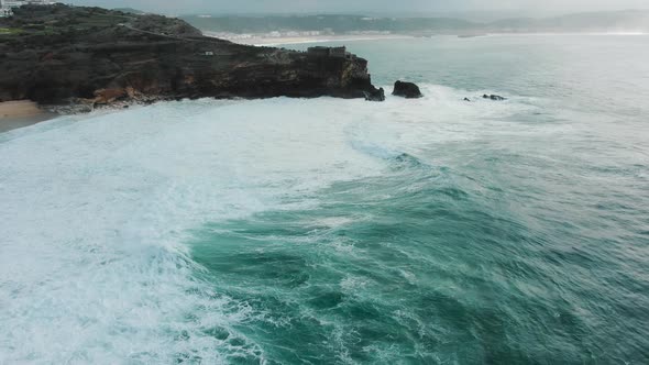 Lighthouse on Steep Cliff Near Ocean on Rainy Day Aerial alt