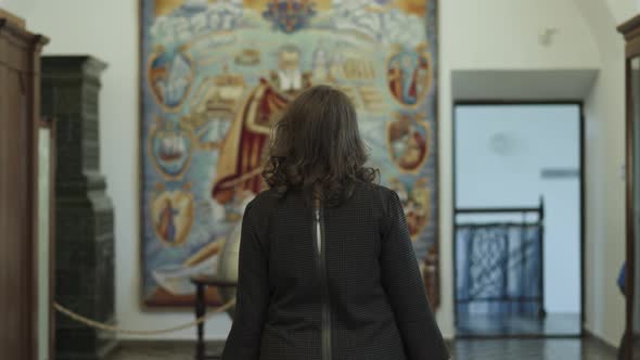 Young Woman in Glasses Walks of Old Library Looks Around Admiringly alt
