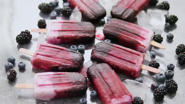 Homemade Blackberry and Cream Ice-creams or Popsicles with Frozen Berries on Black Slate Tray alt