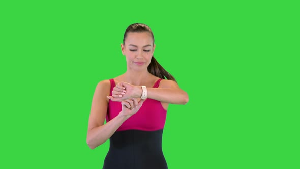 Attractive Sporty Woman Looking at Smart Bracelet While Running on a Green Screen Chroma Key