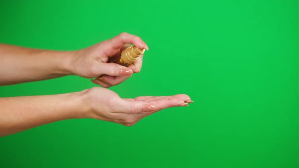 Female Hands Pushing Dispenser on Green Background Using Liquid Soap alt
