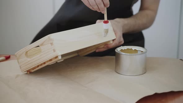 Artisan Applies White Dissolving Clear Lacquer Liquid to Wooden Surface of Box alt