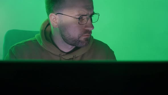 A Caucasian Man in Glasses Works on the Computer Types Checks the Information Coding Studying alt