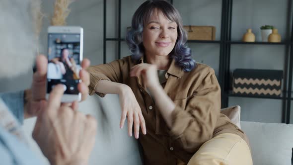 Beautiful Young Woman Posing for Camera While Male Hands Taking Pictures with Smartphone alt