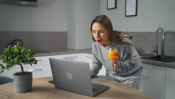 Woman Standing in Home Cozy Kitchen Leaning Over the Table and Communicates Via Video Link with alt