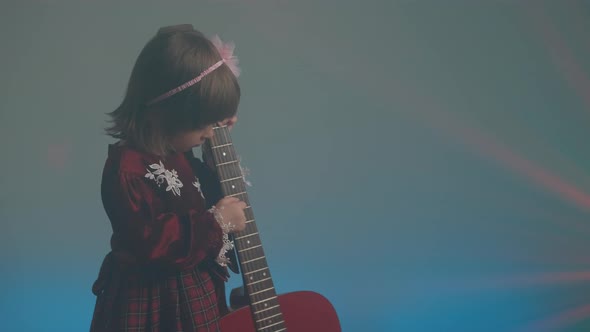 Little Girl in a Vintage Dress Plays an Acoustic Guitar Like a Double Bass