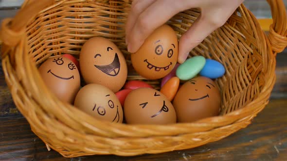 Stack of Hand Drawn Smiley Eggs on Straw Basket with Colorful Candy Easter Preparation Holiday Mood alt