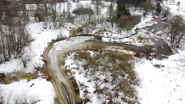 Aerial drone view of a river meandering around a corner in the winter forest. Recorded in Vahiküla F alt