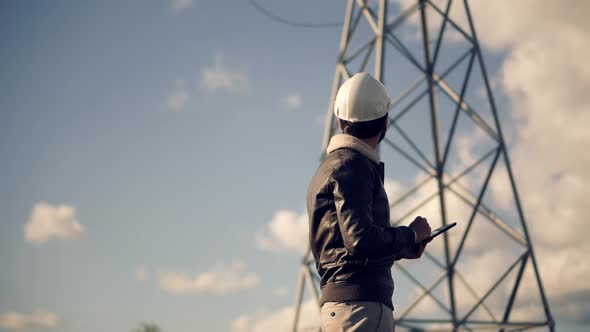 Constructor Inspect High Voltage Tower. Engineer In Hard Hat Maintenance Electricity Transmission. alt