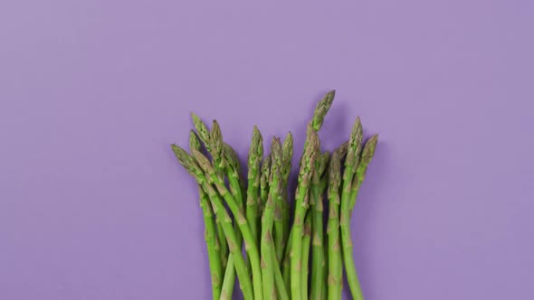 Video of fresh asparagus with copy space over lilac background alt