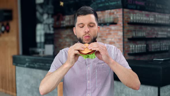 Casual Attractive Male Biting Desired Delicious Hamburger with Meat Lettuce and Vegetable alt